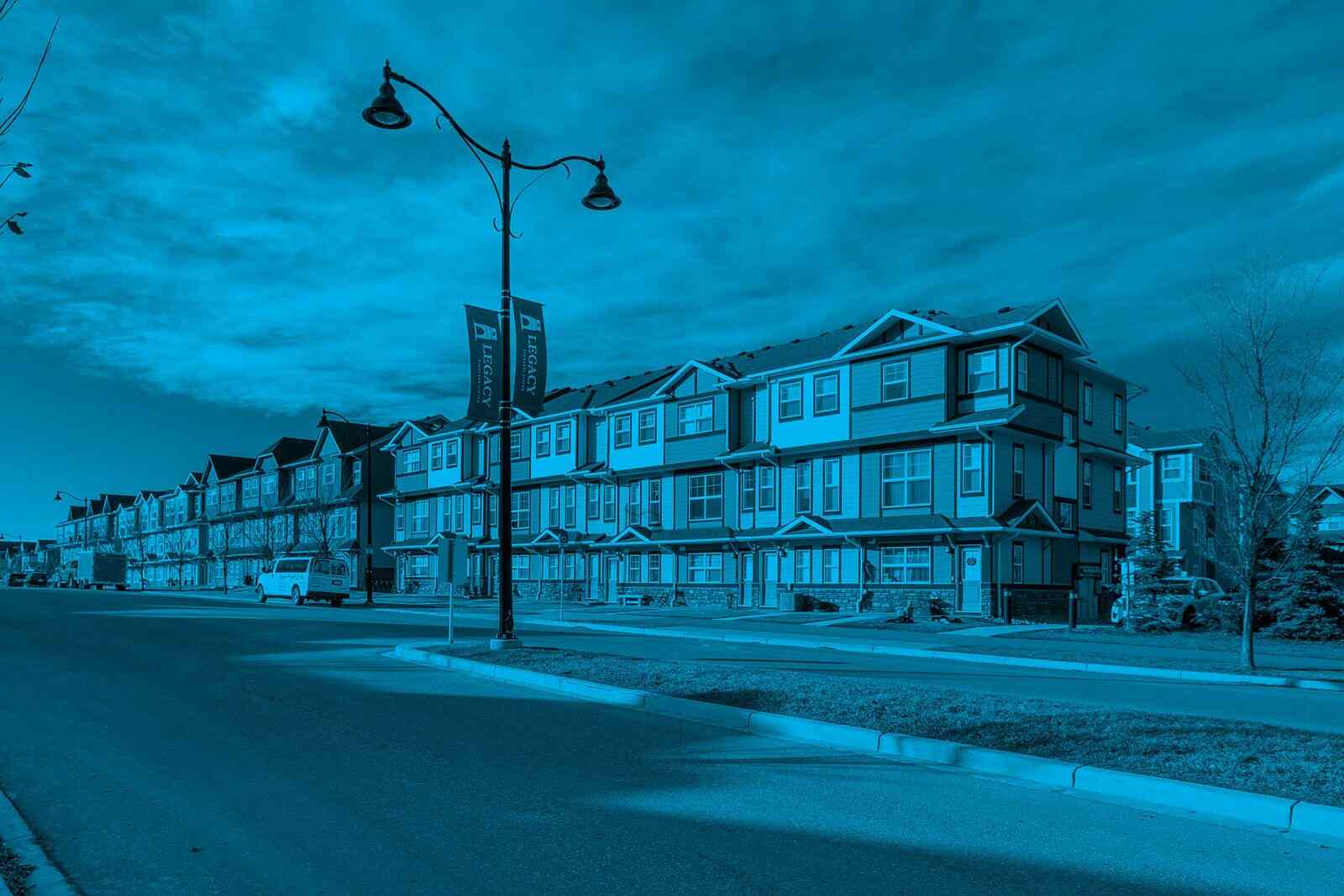 Blue-toned townhouse condominium community with multi-unit residential buildings along a landscaped street, representing condo board roles and responsibilities in overseeing property management, governance, maintenance, and community operations.