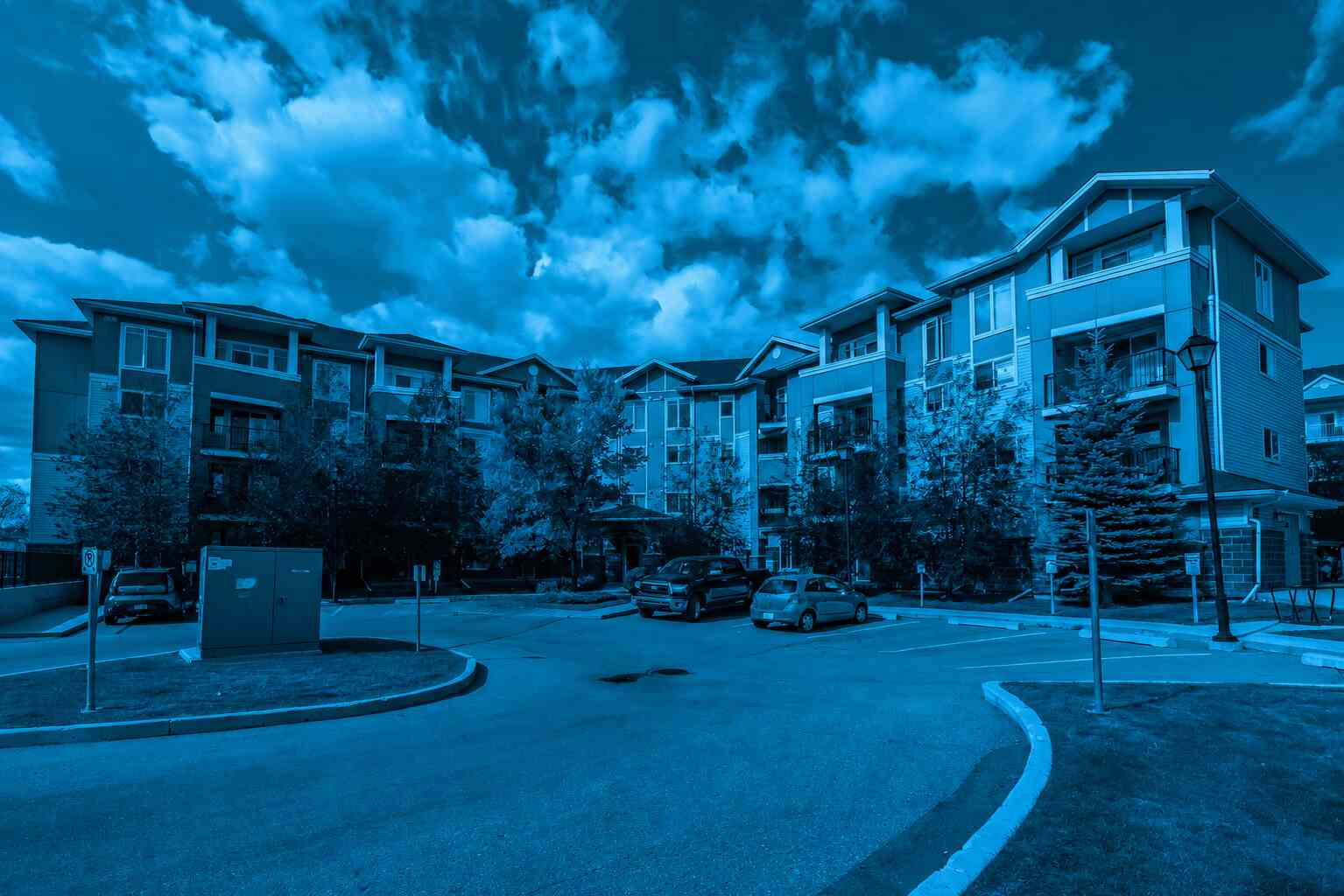 Blue-toned condominium complex with multi-storey residential buildings, parking area, and landscaped grounds, representing a condo performance audit focused on building condition, operational efficiency, and long-term property management planning.